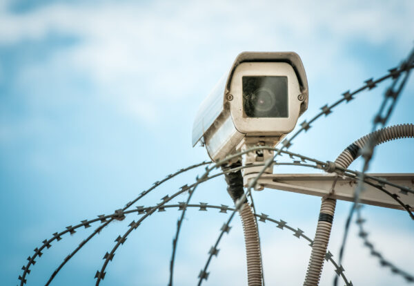 shutterstock_132392237_Close up view of security camera hanging among barbwire